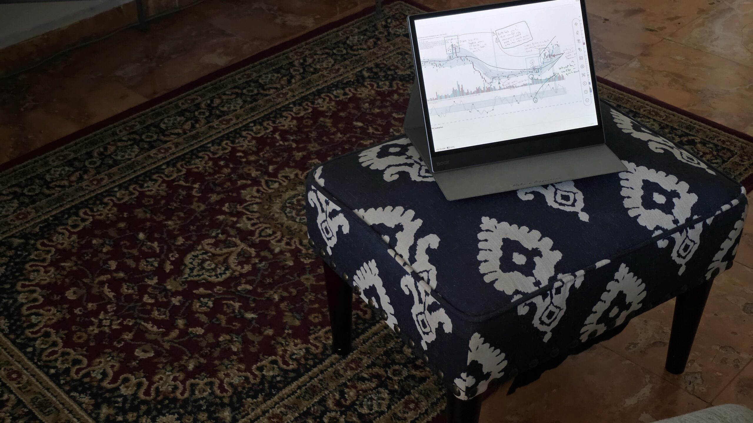 Boox Tab XC showing trading charts resting on a footstool
